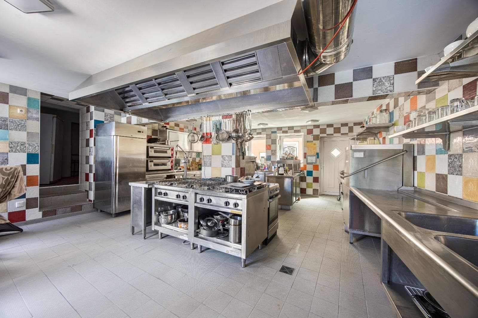 View into the professional kitchen with gas range and stainless steel