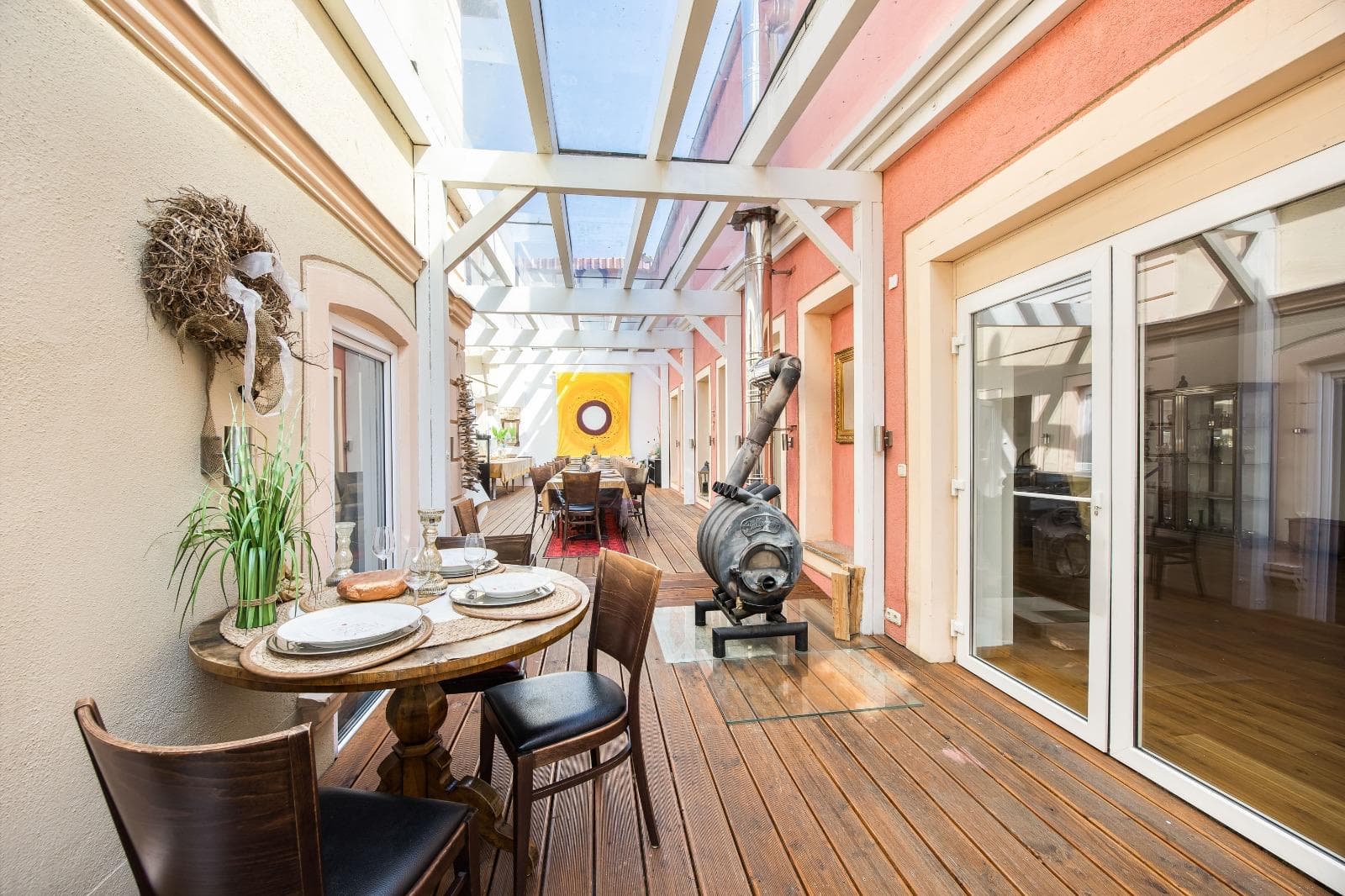 Wintergarten mit Glasdach, warmer roter Wand und langer Tafel