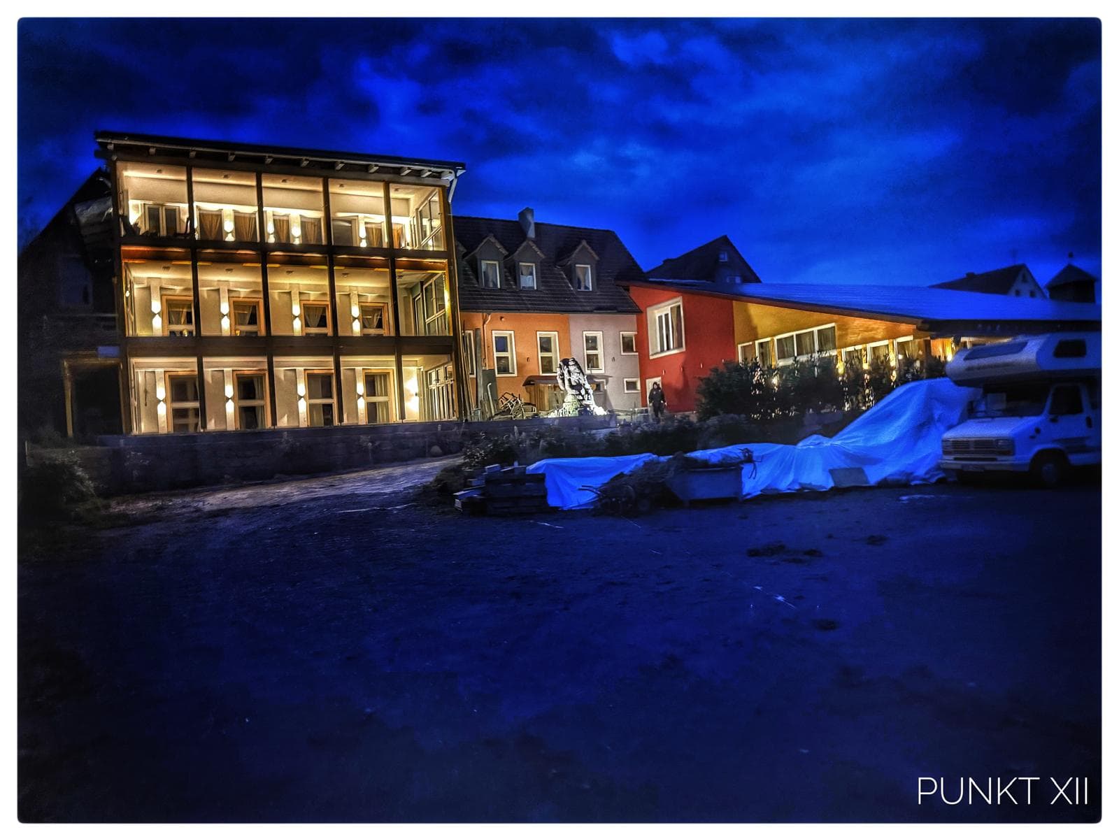 Punkt XII im Steigerwald zur blauen Stunde – der gläserne Wintergarten leuchtet golden in die Dämmerung