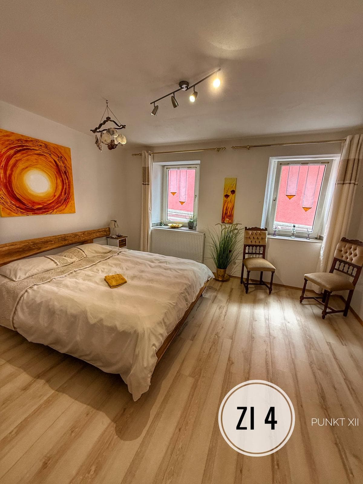 Helles Gästezimmer mit Doppelbett und Sonnenbild bei Punkt XII