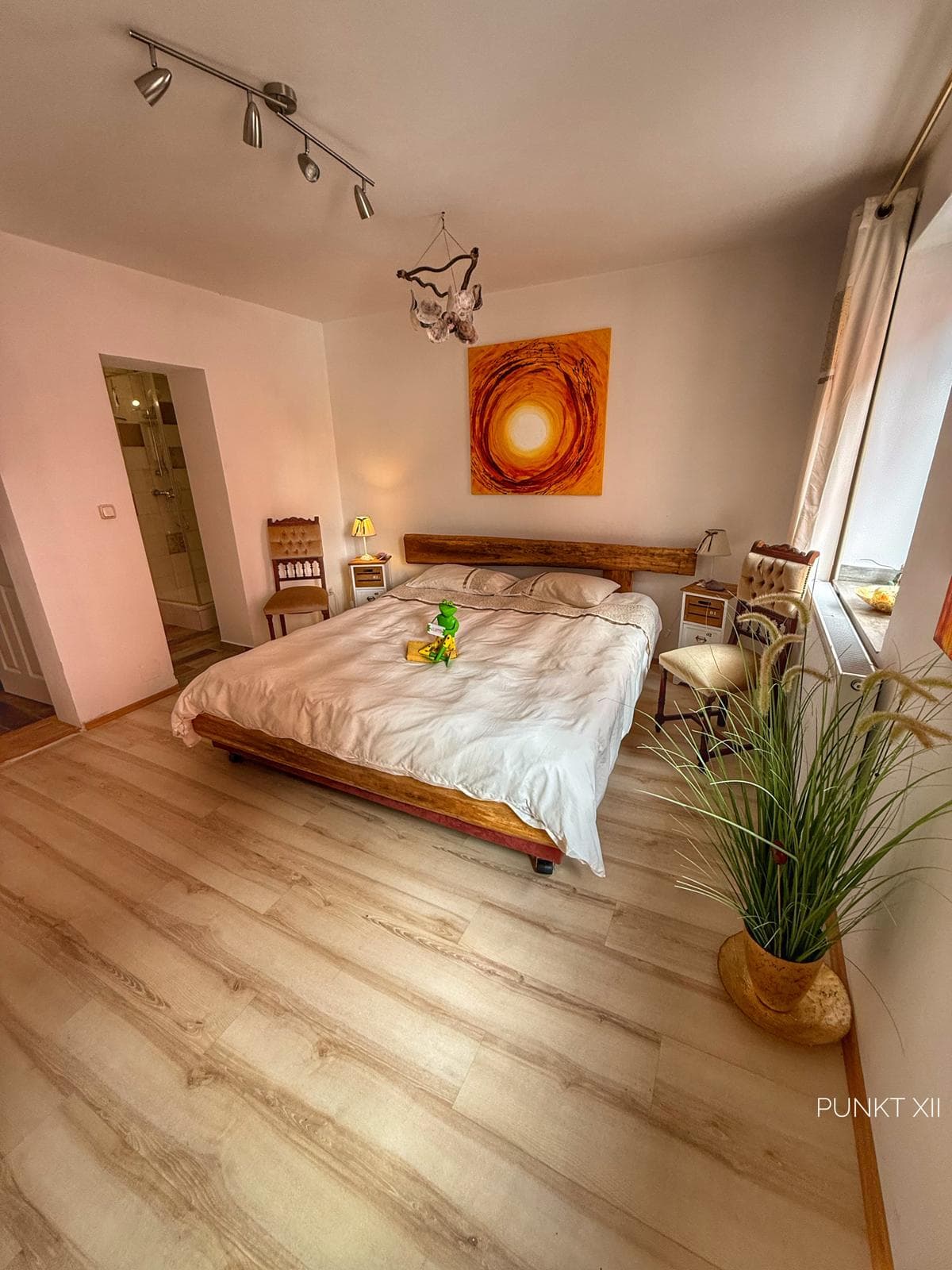 Helles, ruhiges Gästezimmer mit Holzboden und Sonnenbild