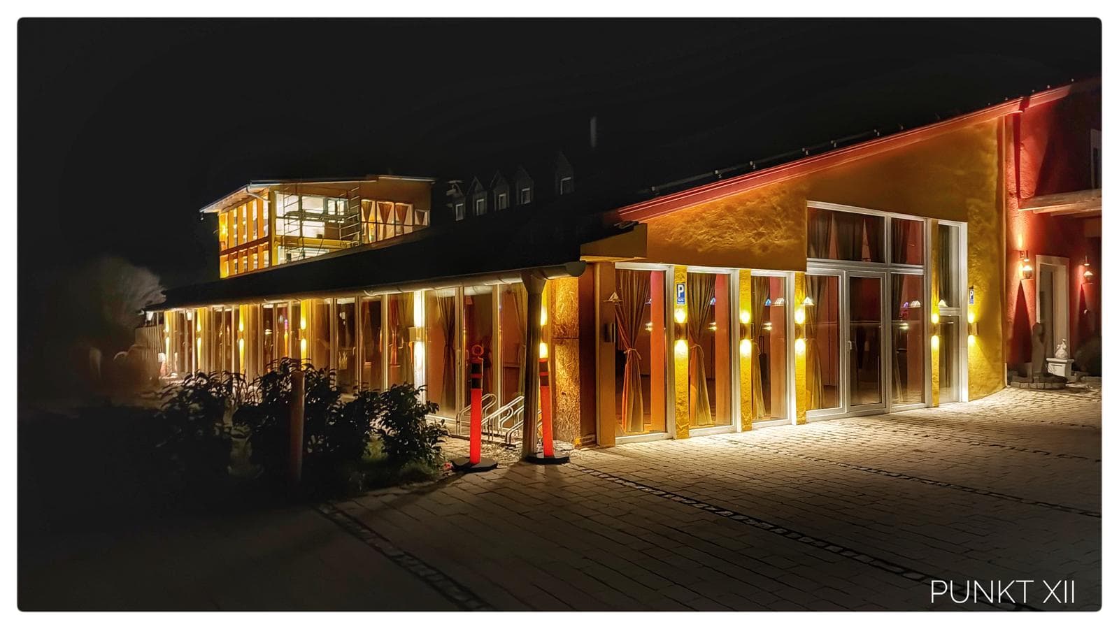 Das golden erleuchtete Haus von Punkt XII bei Nacht im Steigerwald