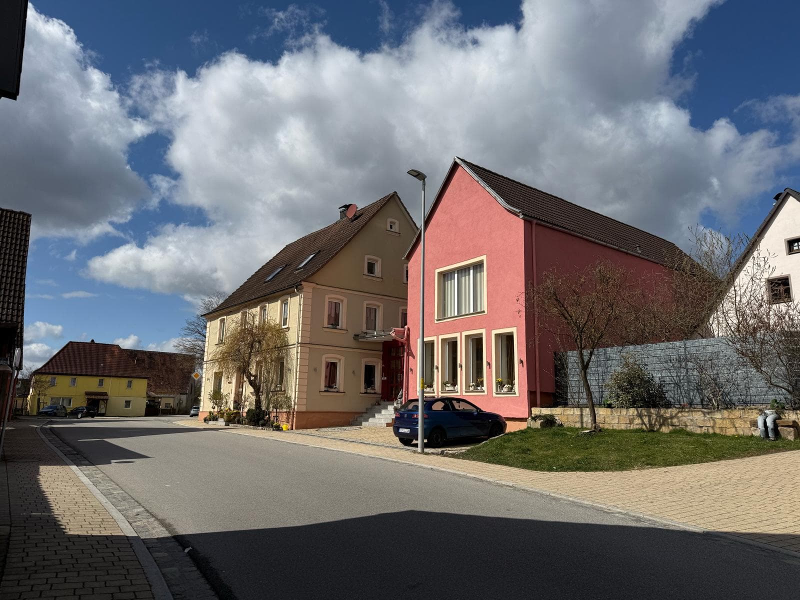 Die ruhige Dorfstraße von Oberrimbach mit terracottafarbenen Häusern unter blauem Himmel